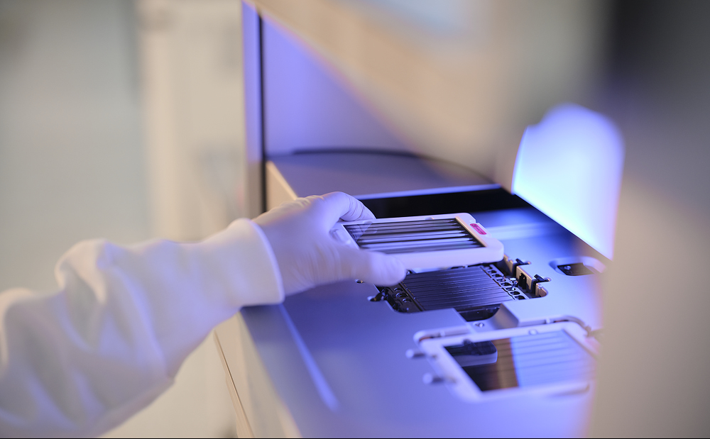 Close up image of a scientist loading a second 25B flow cell cartridge into the NovaSeq X drawer.